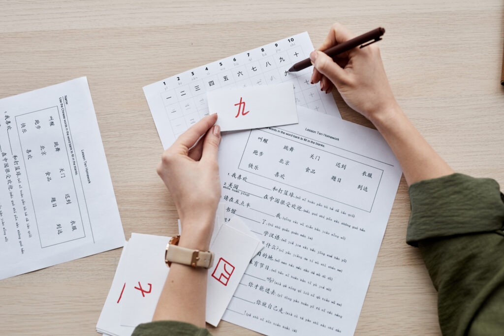 Vista superior de manos realizando traducción japonés realizada por una persona con un boligrafo y notas