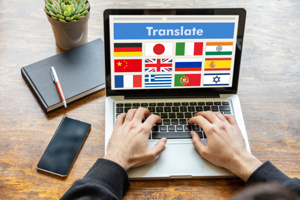 Una persona y una laptop con banderas de países haciendo referencia a la traducción e interpretación del lenguaje