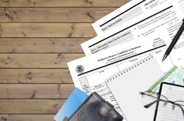Formularios de USCIS y una Green Card sobre un escritorio de madera, listos para el proceso de traducción de documentos oficiales.