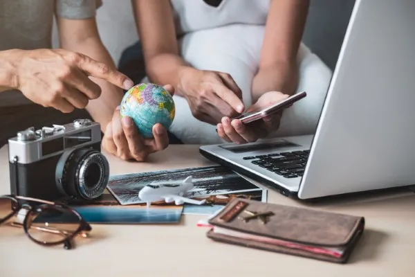 Fotografía de dos personas frente a una computadora usando la traducción jurídica y sosteniendo un globo terráqueo.