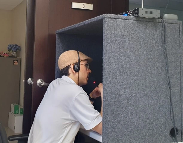 Fotografía de un experto multilingüe sentado en una silla en una cabina de una agencia de traducción.