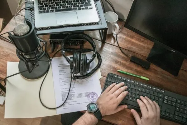 Fotografía de una laptop, un micrófono y unos audífonos sobre un escritorio en una agencia de traducción.