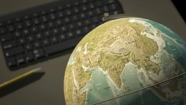 Redacción multilingüe: fotografía desde arriba de un globo terráqueo sobre una computadora y un lápiz a lado.