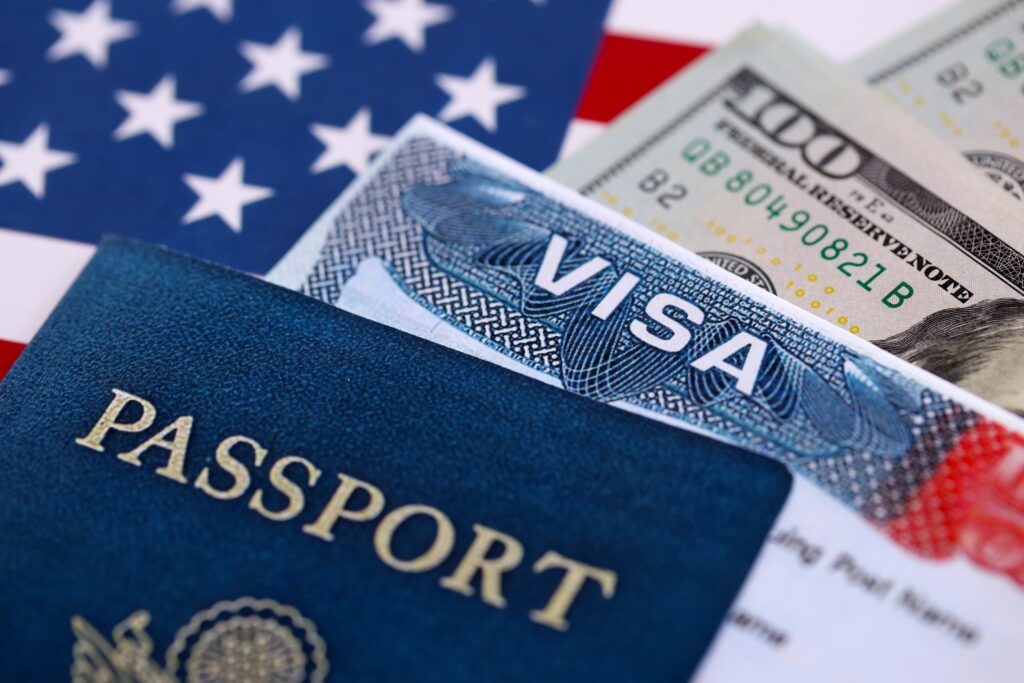 Requisitos para visa de turista: fotografía de una visa color azul sobre dólares y una bandera de Estados Unidos.