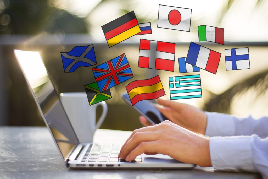 Transcreación: Fotografía de una persona escribiendo en una laptop y arriba de ella banderas de diferentes países.