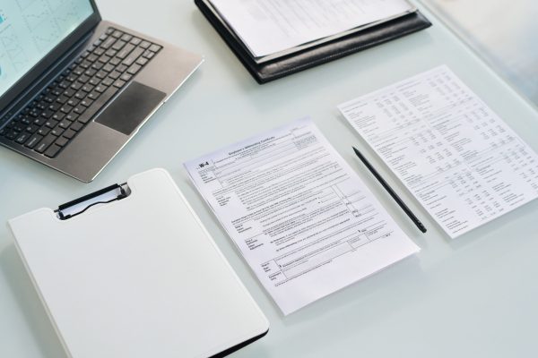 Laptop sobre escritorio blanco junto a documentos realizados por un perito traductor de Babel Traductores