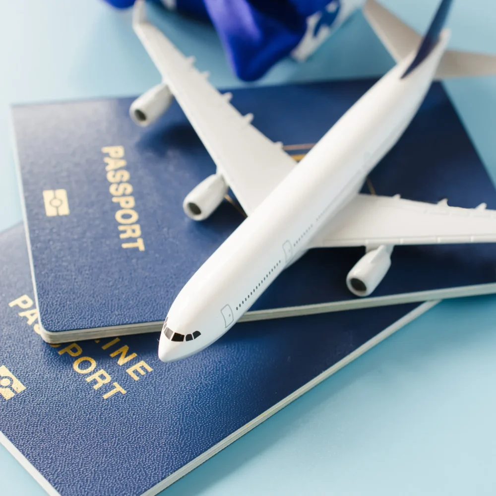 Requisitos para visa de turista: Fotografía de un avión color blanco sobre visas color azul rey en fondo color azul claro.