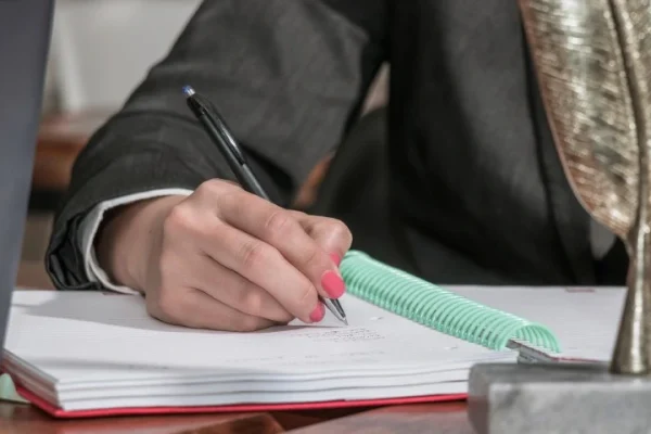 La mano de una mujer sosteniendo una pluma mientras realizar un trabajo.