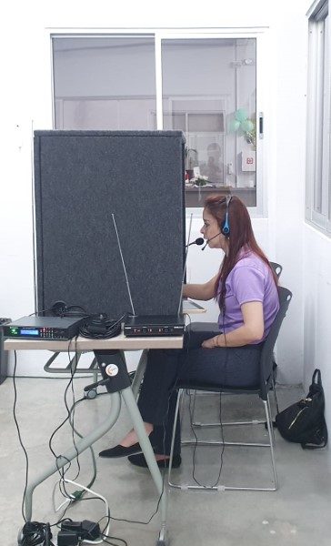 Una mujer realizando una traducción en una cabina en tiempo real.